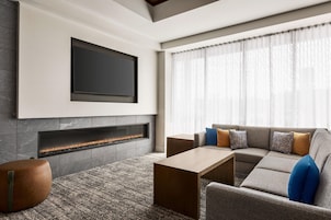 Una sala de estar moderna con una televisión de pantalla plana sobre una chimenea, un sofá modular con cojines y una mesa de centro.