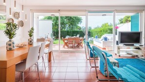 Un grand espace de vie comprenant une table à manger, des chaises, un canapé et un téléviseur.