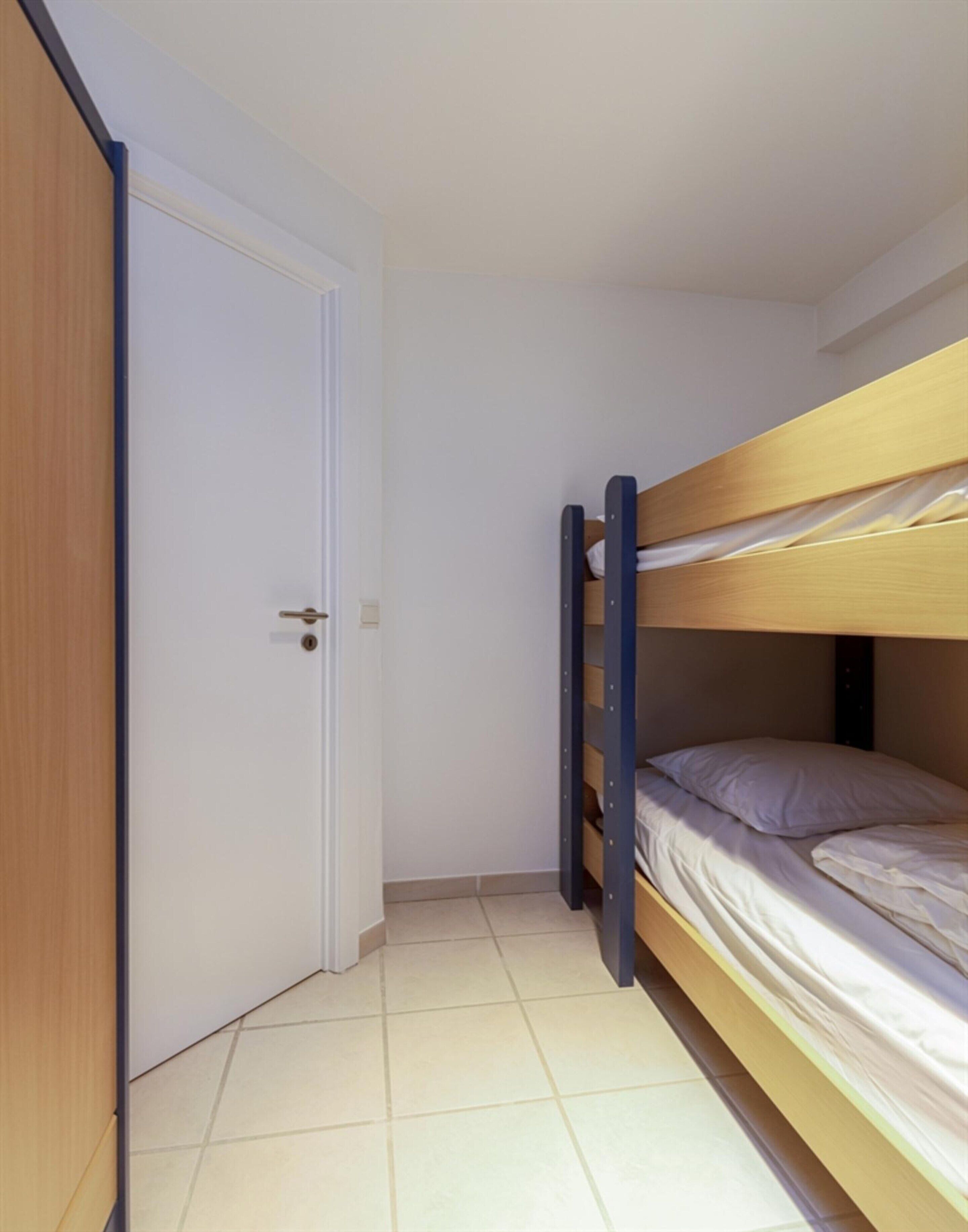 A small, compact room with a bunk bed and a door.