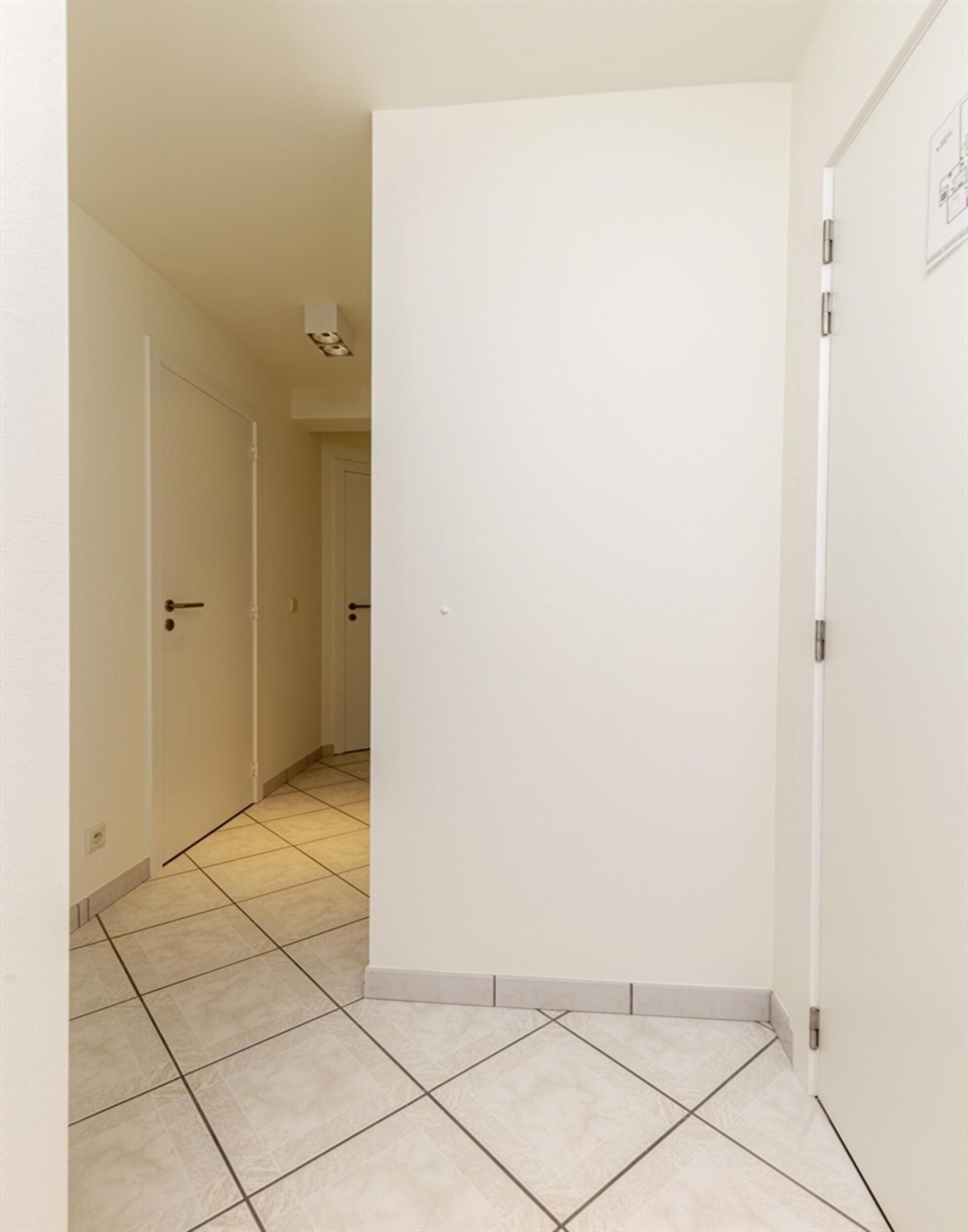 A narrow hallway with tiled flooring and white walls.