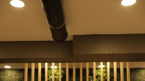 A room with a wooden floor, a potted plant, and a wall with vertical slats and greenery. - Elite World GO  İnegöl  (Inegol)