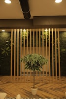 A room with a wooden floor, a potted plant, and a wall with vertical slats and greenery.