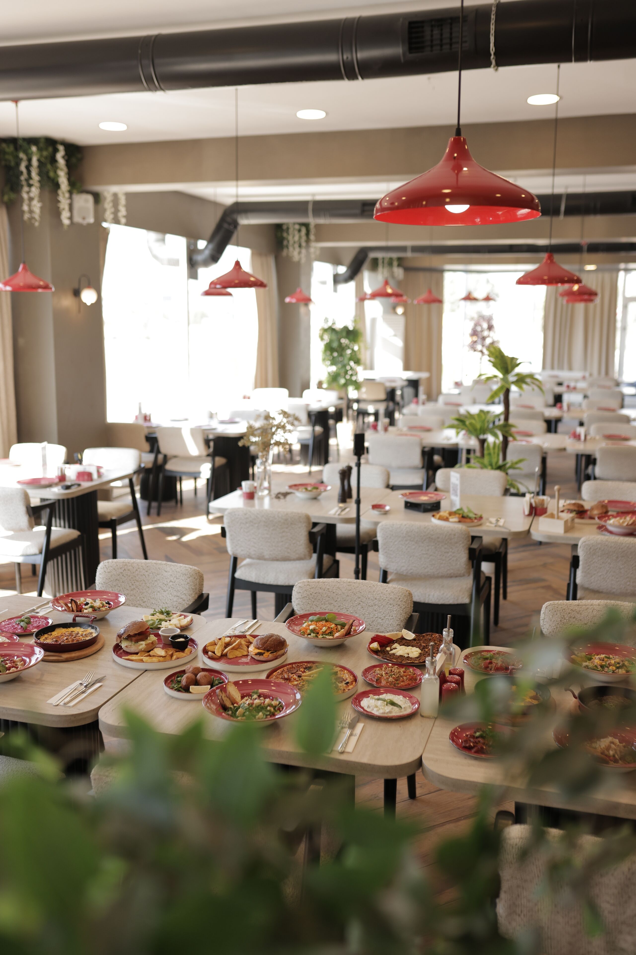 Un restaurante con varias mesas, lámparas colgantes rojas y una variedad de platos.