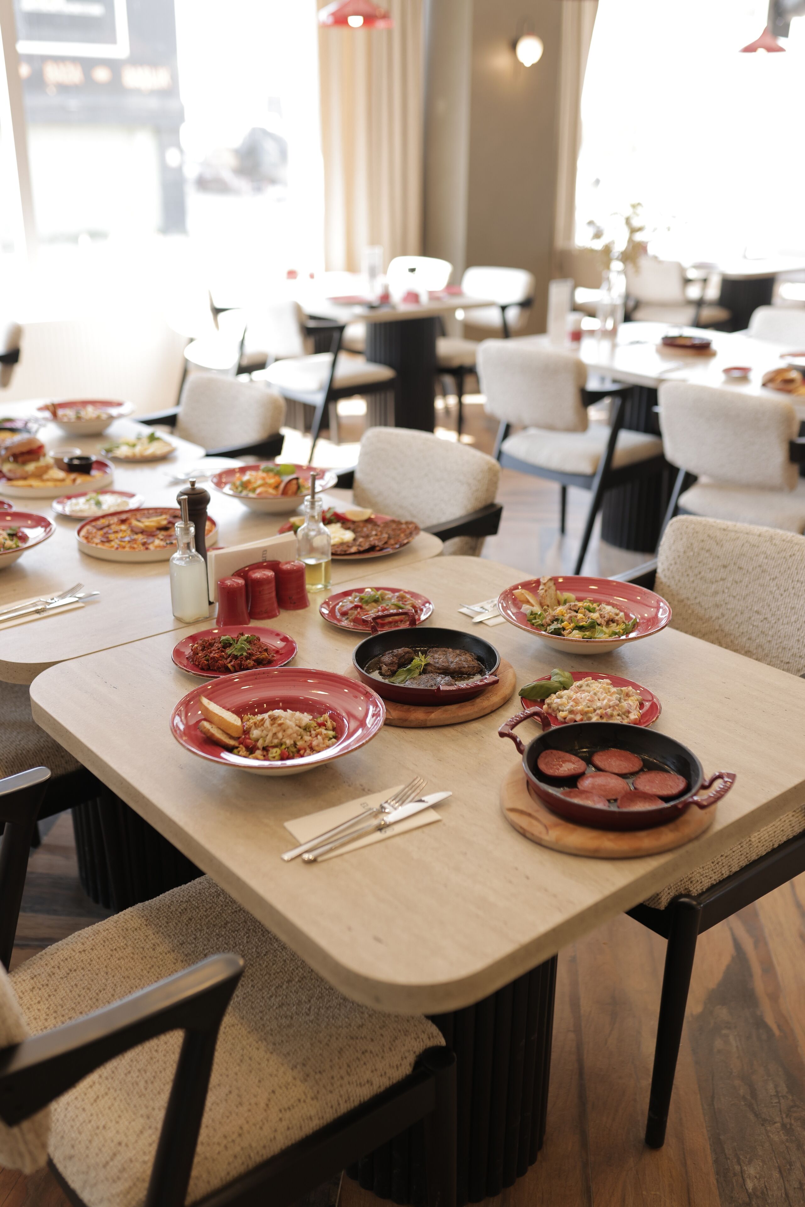 A dining area with multiple tables set for meals, chairs, and various dishes.