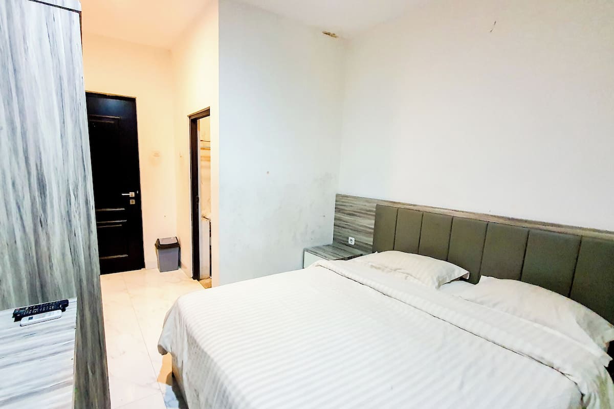 A bedroom with a bed, a nightstand, a TV, and a door.