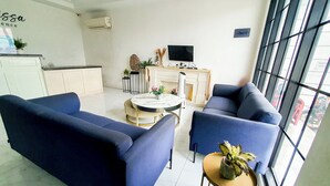 Un salon moderne avec des canapés bleus, une table basse ronde et une cheminée.