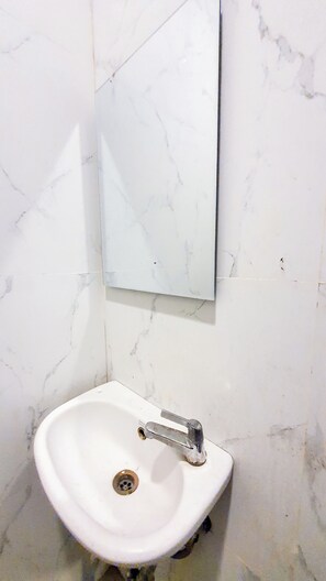 A bathroom with a white sink, a mirror, and marble walls. - La'rissa Residence by ARBA (Karawang)