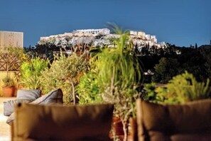 A view of a building on a hill with a patio area in the foreground. - Acropolis Noir Penthouse

 (Athina)