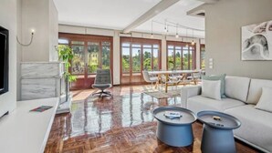A spacious living room with a large window, a dining area, and a modern sofa.