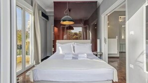 A modern hotel room with a large bed, a hanging pendant light, and a view of the outdoors.