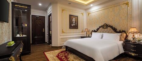 A luxurious hotel room with a large bed, a wooden floor, a chandelier, and ornate wall decorations.