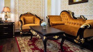 A luxurious room with a gold-trimmed sofa, a matching armchair, a dark wooden coffee table, and a patterned carpet. - Dream Boutique Hotel Da Lat (Xuan Huong - Da Lat)