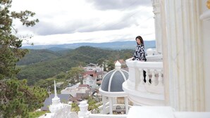 A person standing on a balcony with a view of a town and mountains. - Dream Boutique Hotel Da Lat (Xuan Huong - Da Lat)