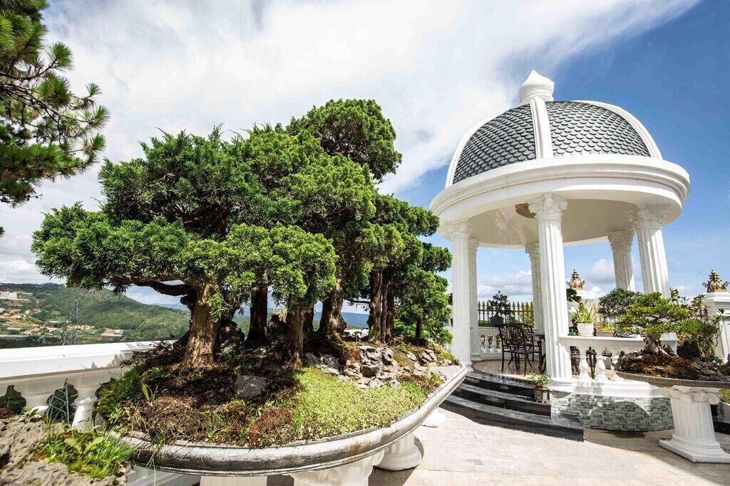 Un gazebo con tetto a cupola, circondato da un giardino curato con alberi e vista sul paesaggio.