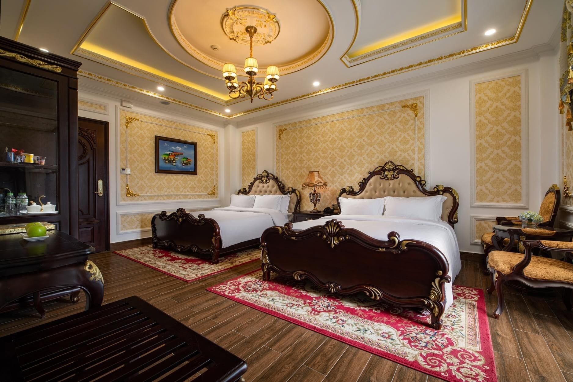 A luxurious bedroom with two ornate beds, a chandelier, and a painting on the wall.