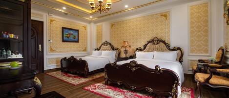 A luxurious bedroom with two ornate beds, a chandelier, and a painting on the wall.