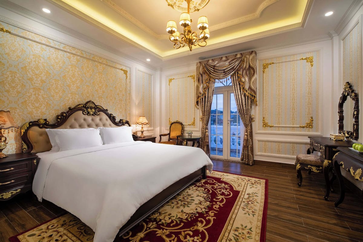 Un dormitorio lujoso con una cama grande, cortinas decorativas y vistas a un cuerpo de agua.