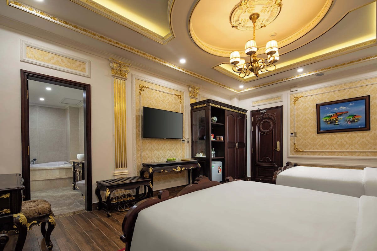 Una lujosa habitación de hotel con una cama grande, televisor, armario y baño con bañera.