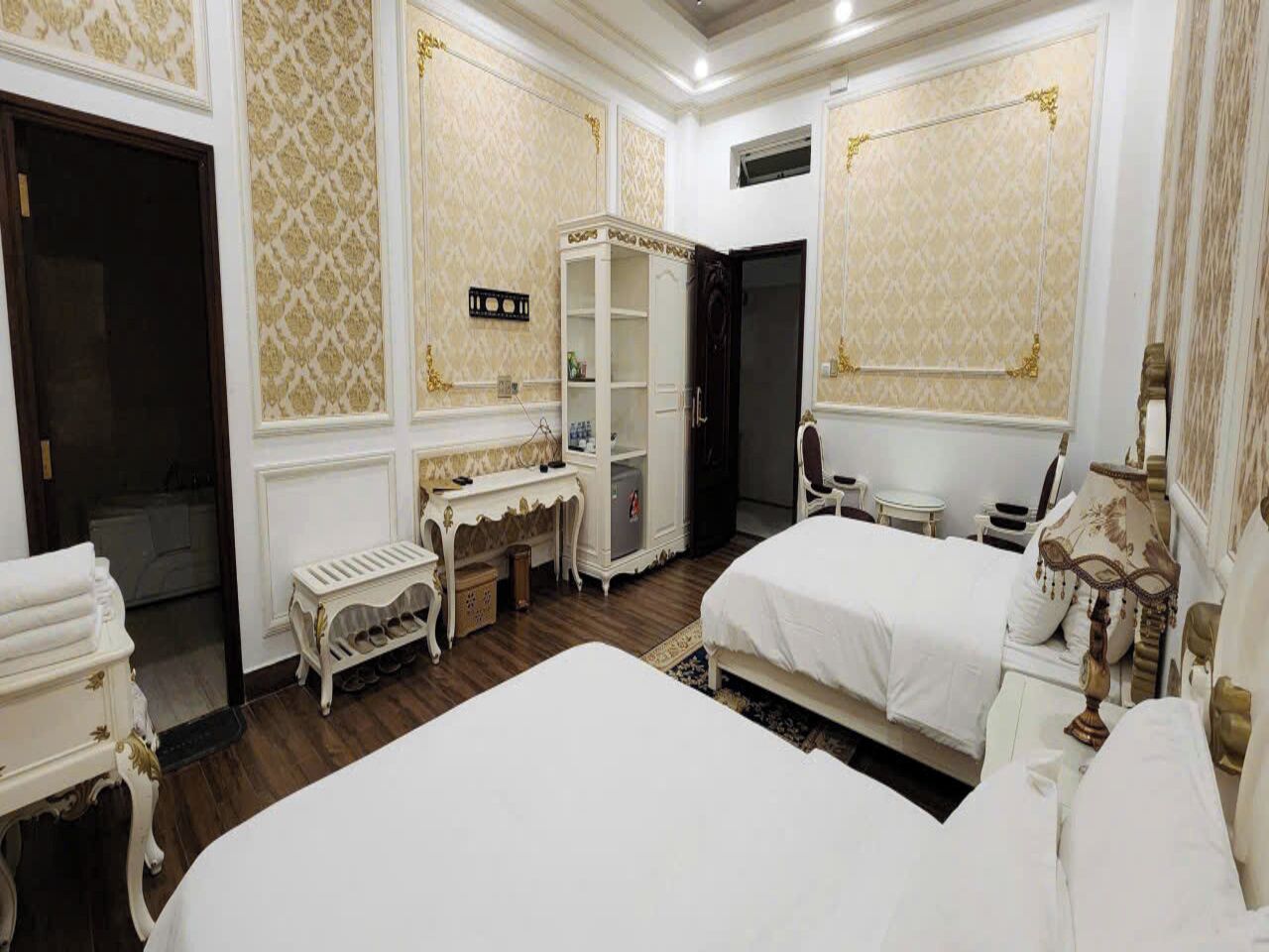 A hotel room with two beds, a vanity, a desk, and a wardrobe.