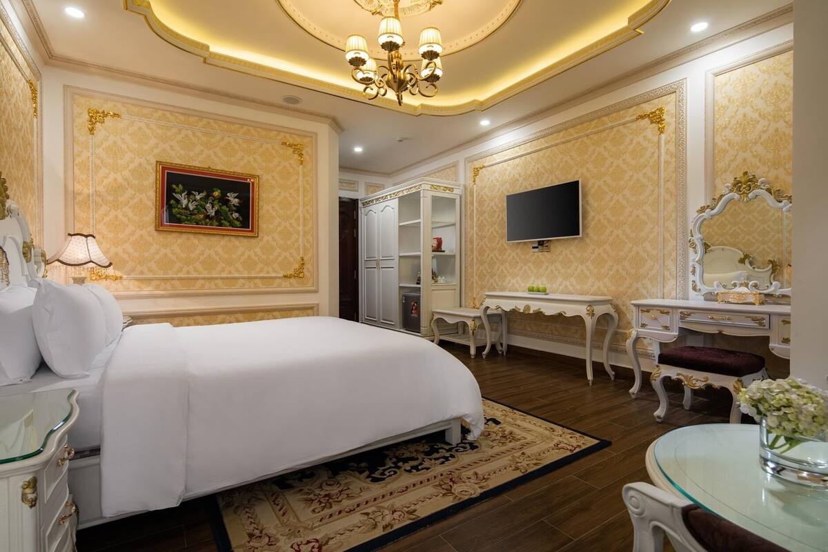 Un dormitorio lujoso con una cama grande, un tocador con espejo, un escritorio y un televisor.