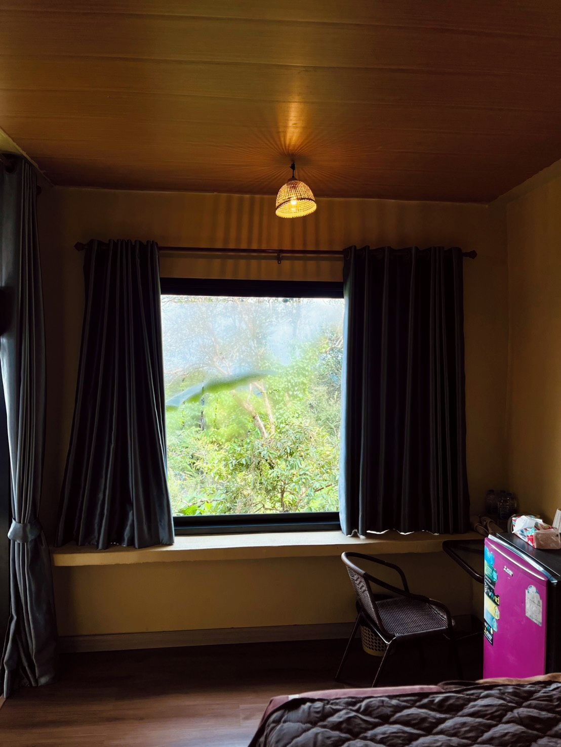 Une pièce avec une grande fenêtre, un bureau, une chaise et un lit.