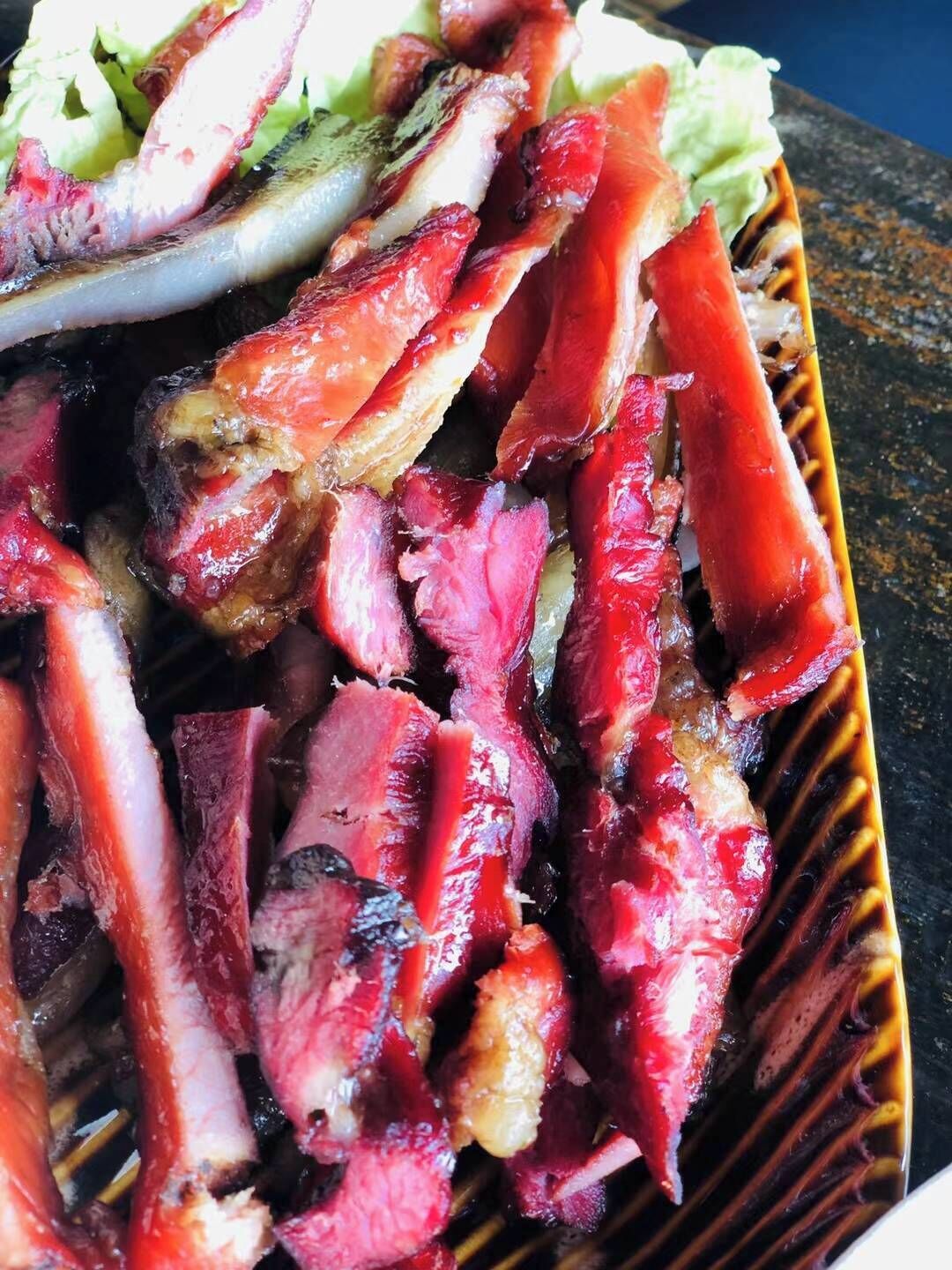 A close-up of grilled meat with visible char marks, served on a ceramic plate with a decorative edge.