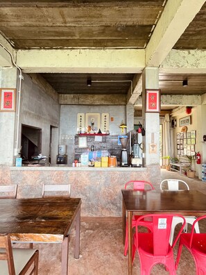 A restaurant with a counter, chairs, and a coffee machine.