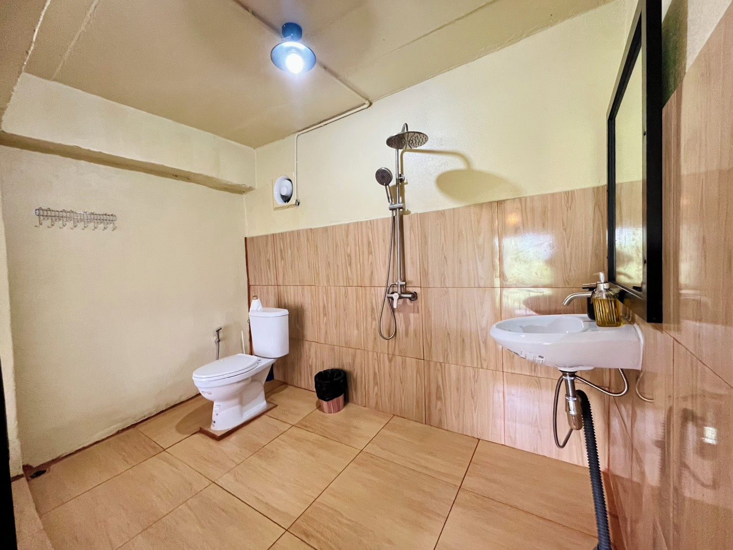 A bathroom with a toilet, bidet, and sink, with wooden paneling on the walls and a ceiling light.