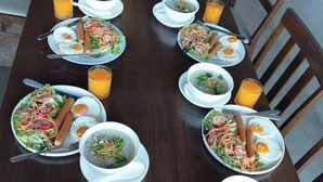 Taula de dinar posta amb plats de menjar diversos, incloent amanides, ous i sopa, juntament amb tasses de suc d'aranja.