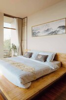 Un dormitorio con una cama grande, plataforma de madera y un cuadro de montañas.