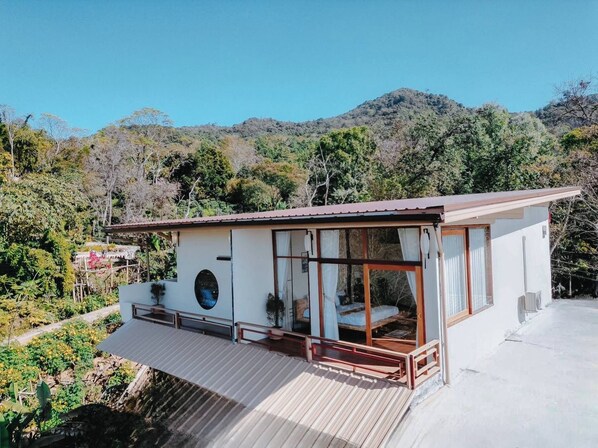 A single-story building with a balcony, large windows, and a view of a mountainous landscape.