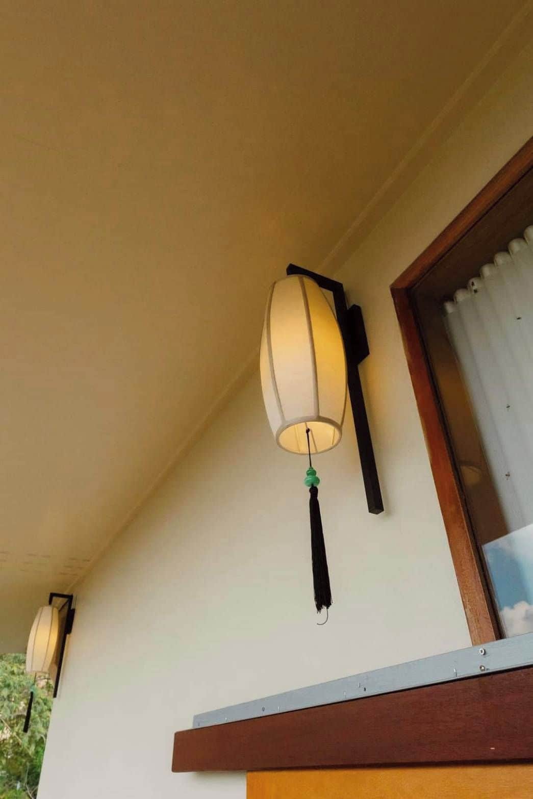 A wall-mounted lamp with a black tassel hanging from it.