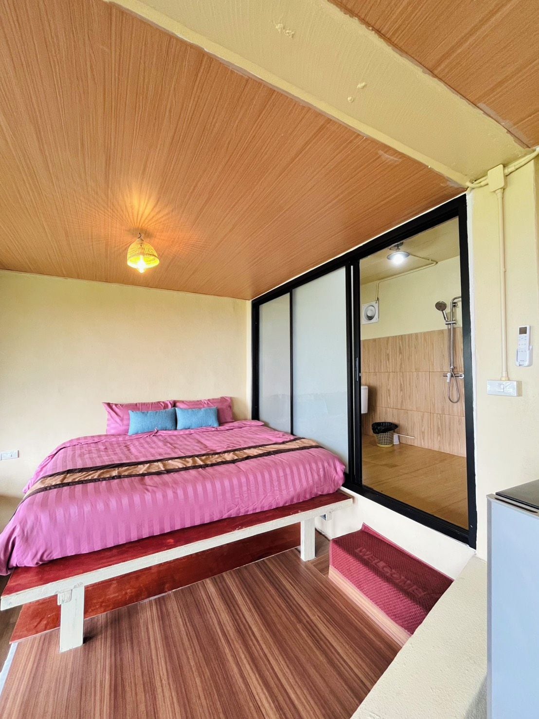 Ein Schlafzimmer mit einem Bett, einer Holzbalkendecke und Blick auf ein Badezimmer.