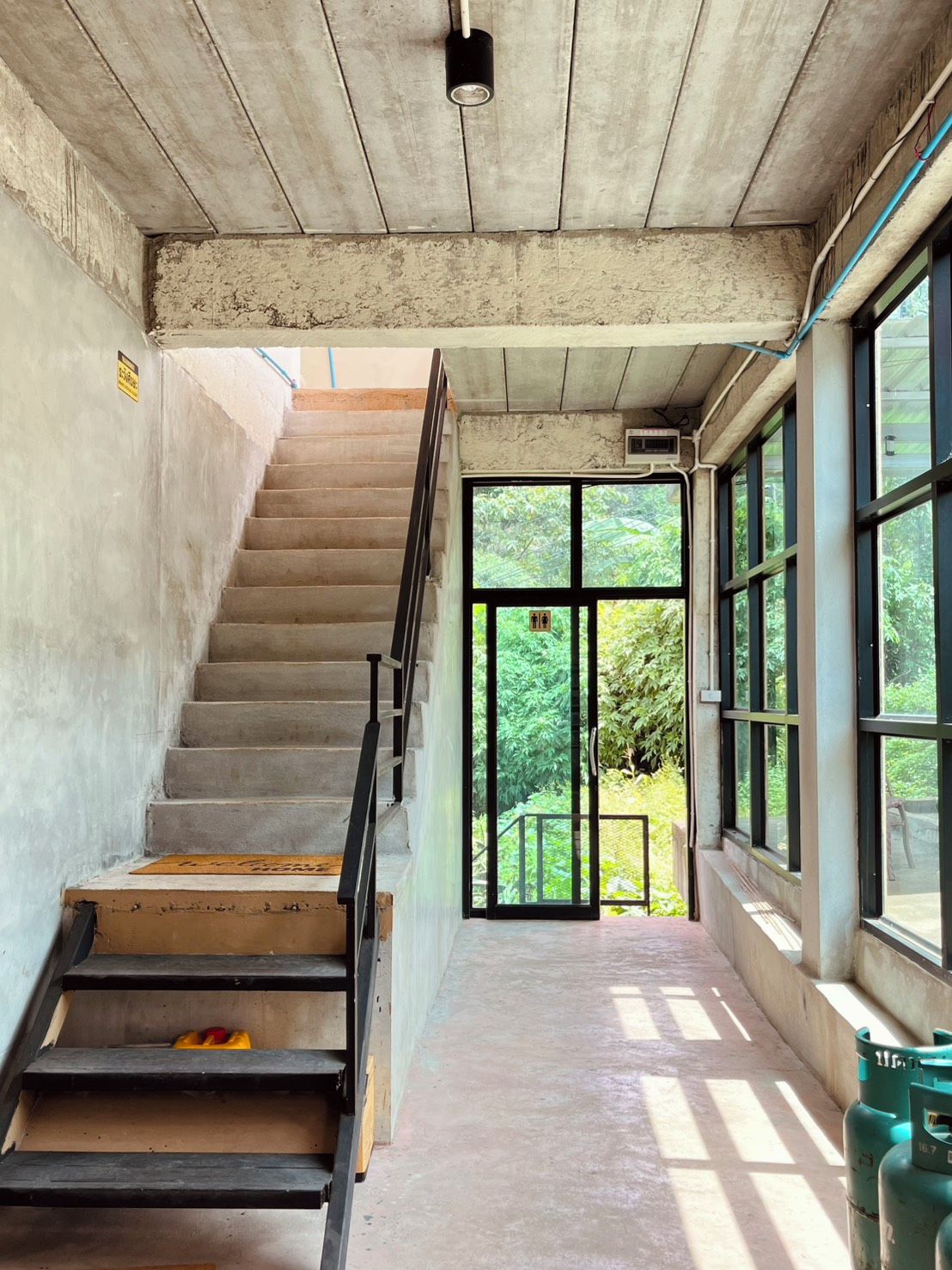 Una escalera que lleva a una puerta con vista a la vegetación.
