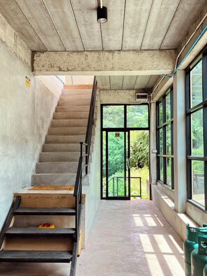 A staircase leading to a door with a view of greenery outside.