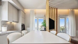 Een moderne woonkamer met een grote witte tafel, witte banken en een televisie.