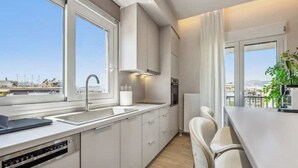 Een moderne keuken met een vaatwasser, een spoelbak en een raam met uitzicht op een stadsbeeld.