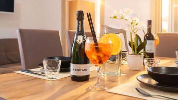 Una mesa de comedor con una botella de vino Ferrari, una copa de vino y un cóctel con una rodaja de naranja.