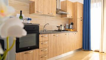 A modern kitchen with wooden cabinets, a built-in oven, and a stainless steel sink.