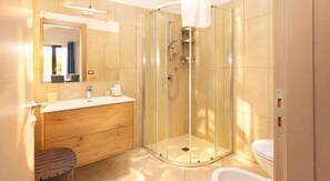 A modern bathroom with a glass-enclosed shower, a wooden vanity, and a toilet. - Kalispera Residence  (Scalea)