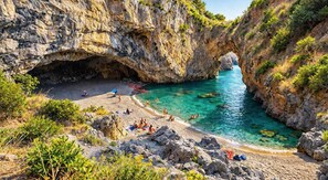 A coastal beach with rocky cliffs, clear turquoise water, and a cave entrance. - Kalispera Residence  (Scalea)