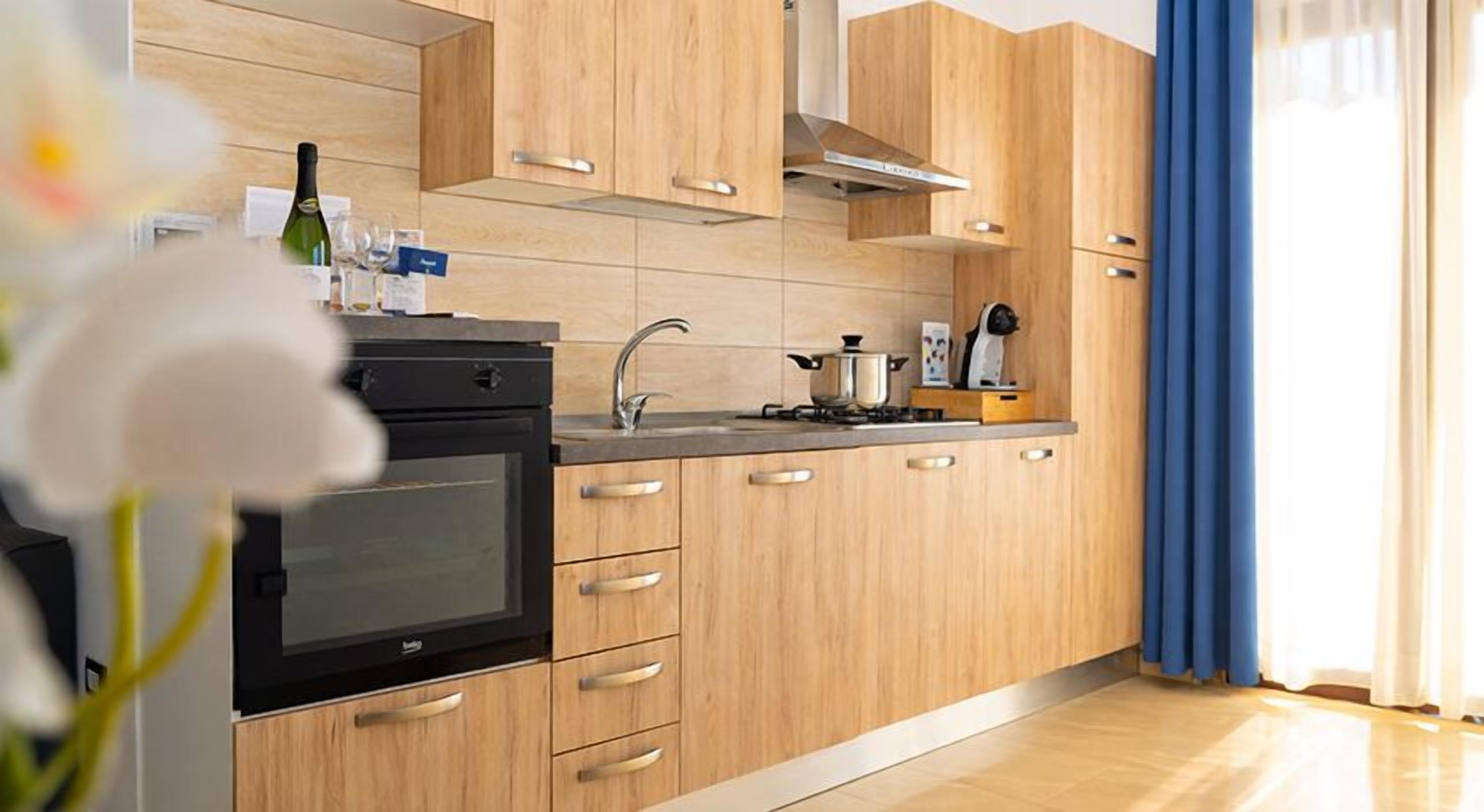 Una cocina moderna con armarios de madera, estufa de acero inoxidable y horno empotrado.