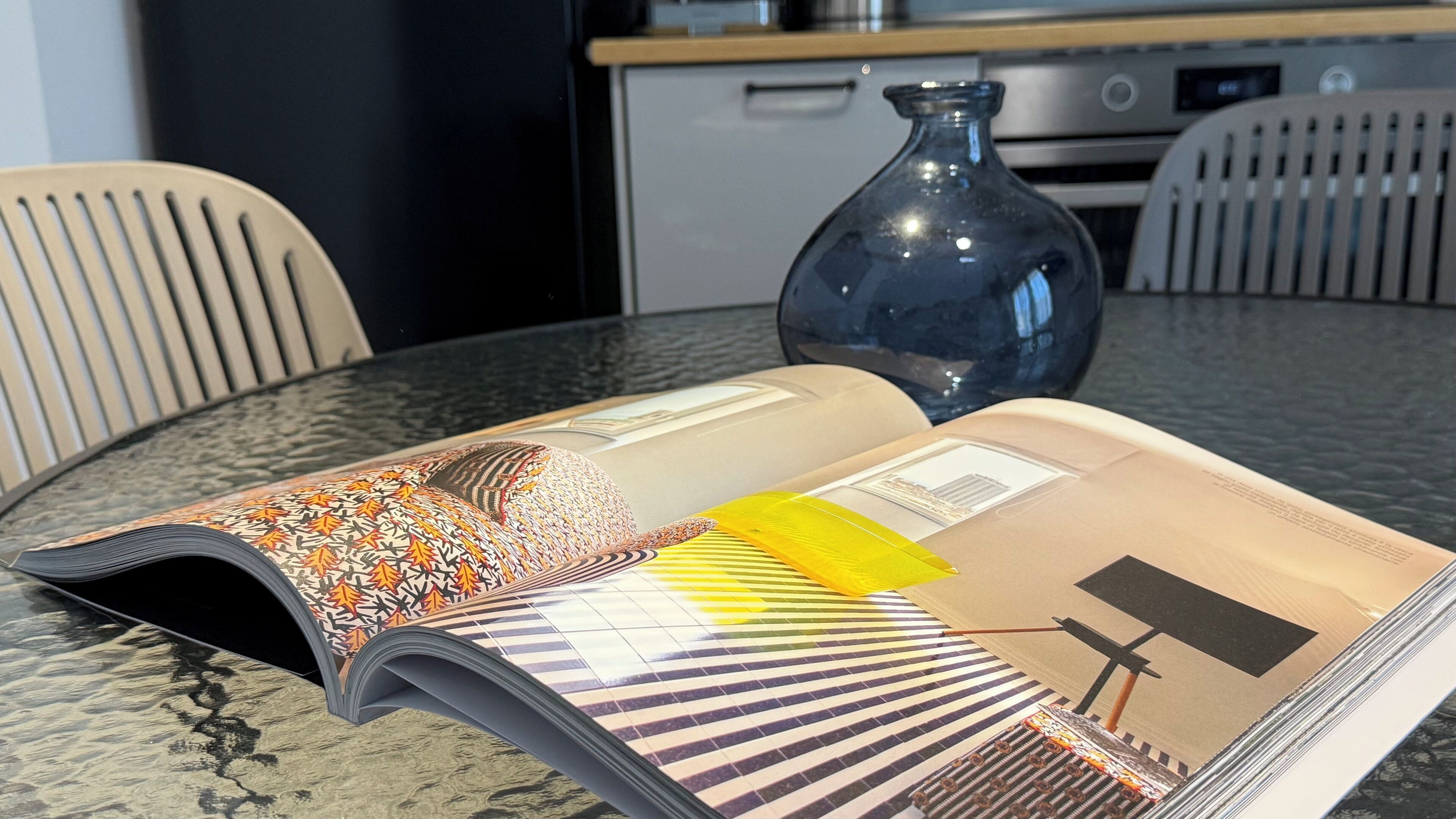 Un magazine est ouvert sur une table, avec une cuisine en arrière-plan.