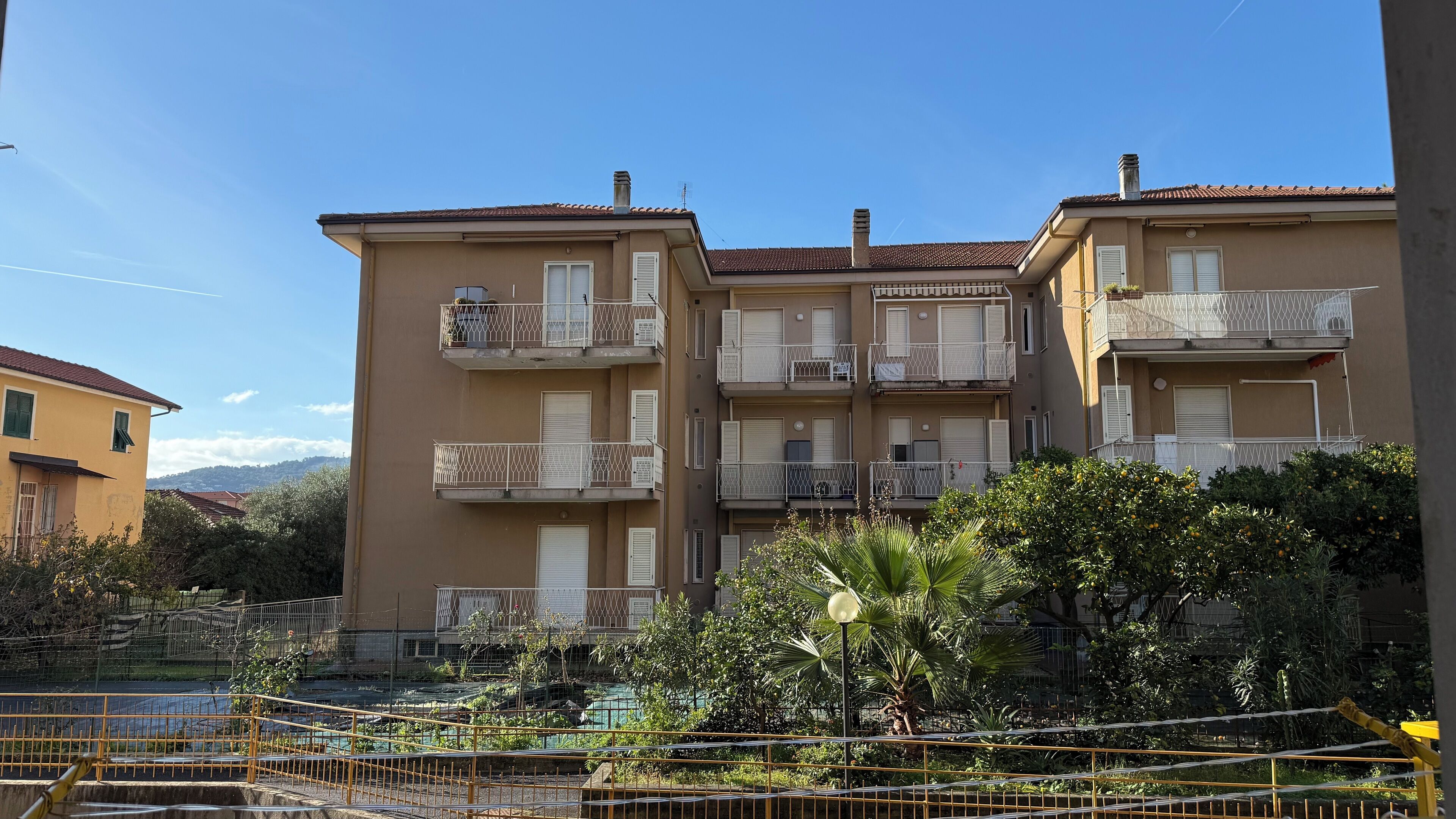 Un edificio residenziale a più piani con balconi, una piscina e aree verdi circostanti.
