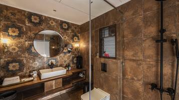 Un baño con un espejo grande, un lavamanos y una zona de ducha.