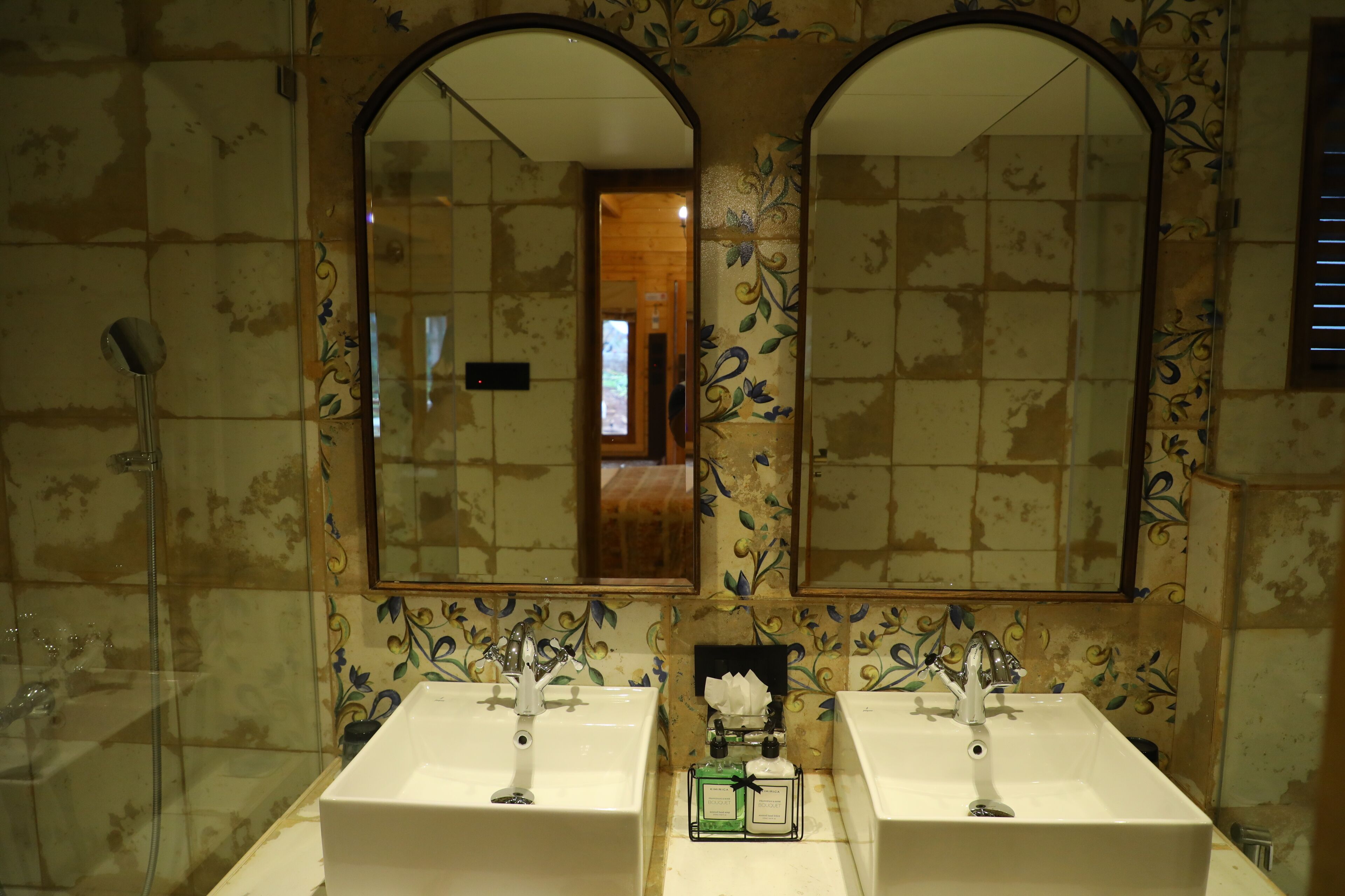 A bathroom with two sinks, a mirror, and a shower.