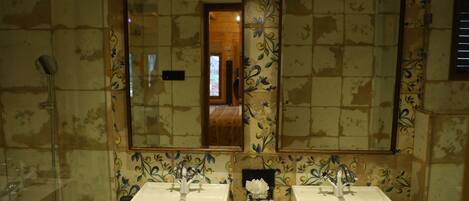 A bathroom with two sinks, a mirror, and a shower.