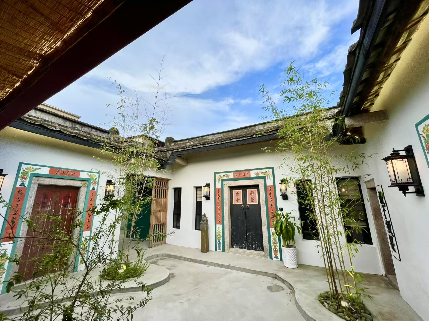 A traditional courtyard with a tiled roof, wooden doors, and potted plants.