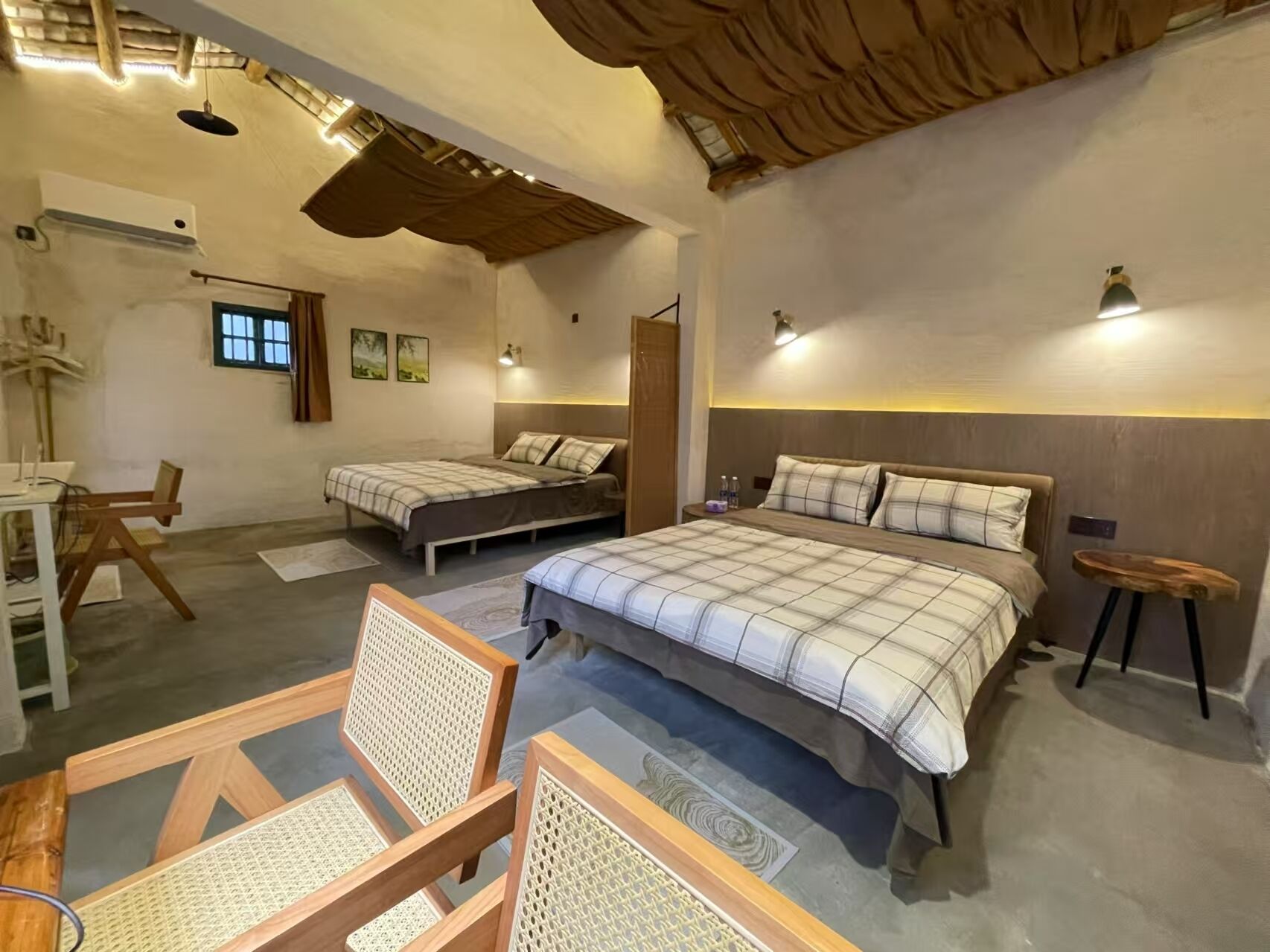 A cozy bedroom with two beds, a desk, and chairs.