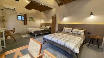 A cozy bedroom with two beds, a desk, and chairs.